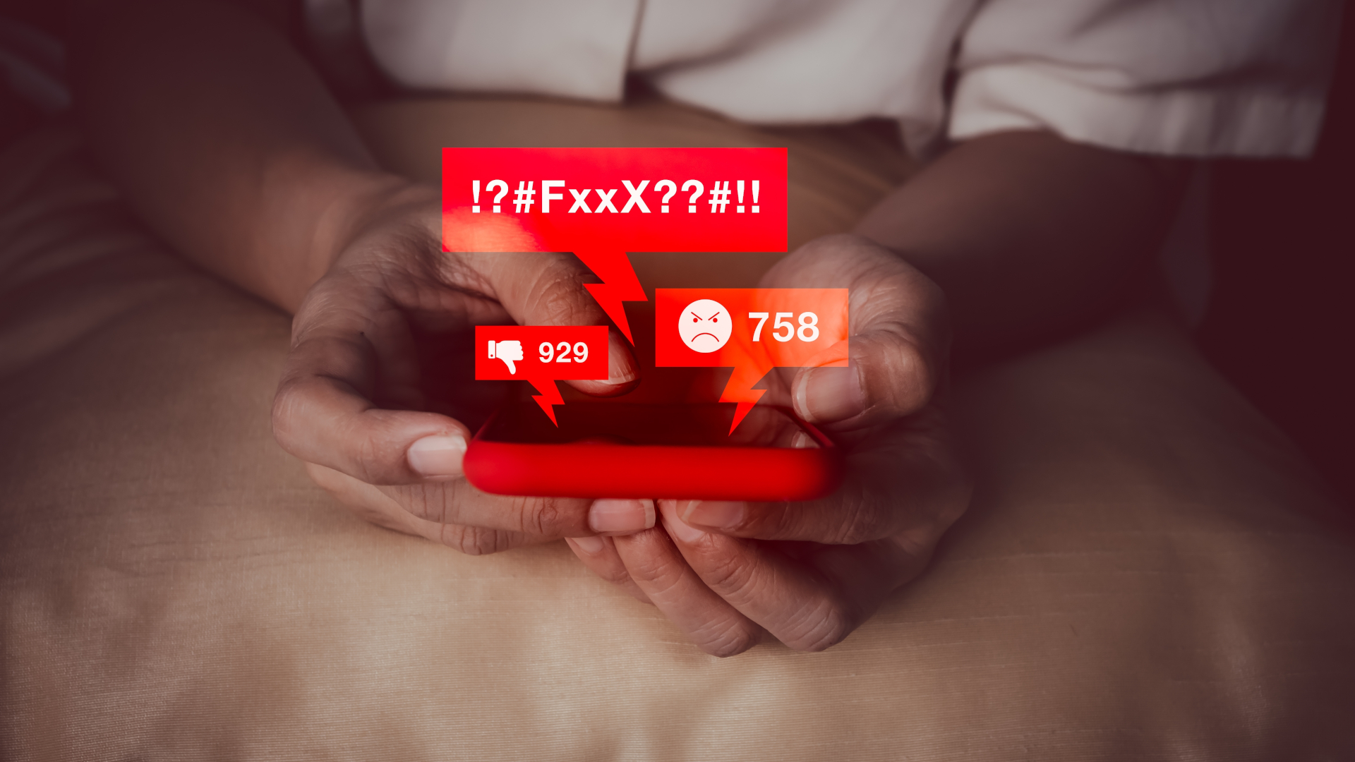 Nahaufnahme zweier Hände, die ein Smartphone halten; darüber sind rote Symbole gelegt: Daumen runter, wütender Smiley, kantige Sprechblase mit dem Inhalt '!?#FxxX??#!!', was wütende Irritation ausdrückt.
