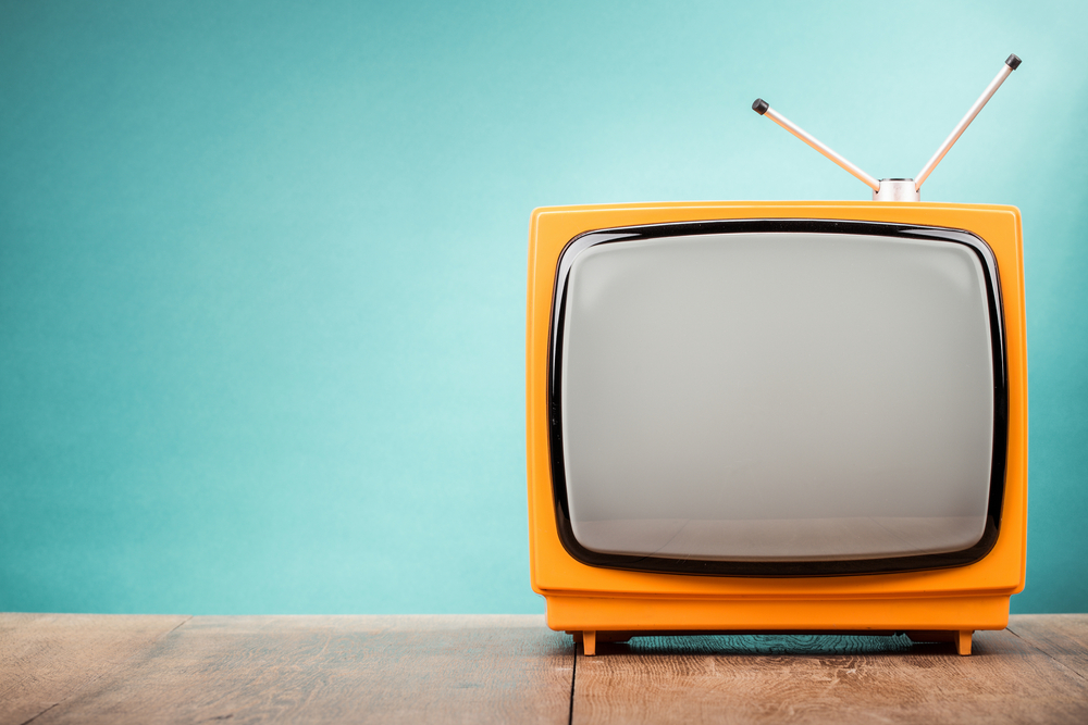 Ein gelber Röhrenfernseher vor einem himmelblauen Hintergrund