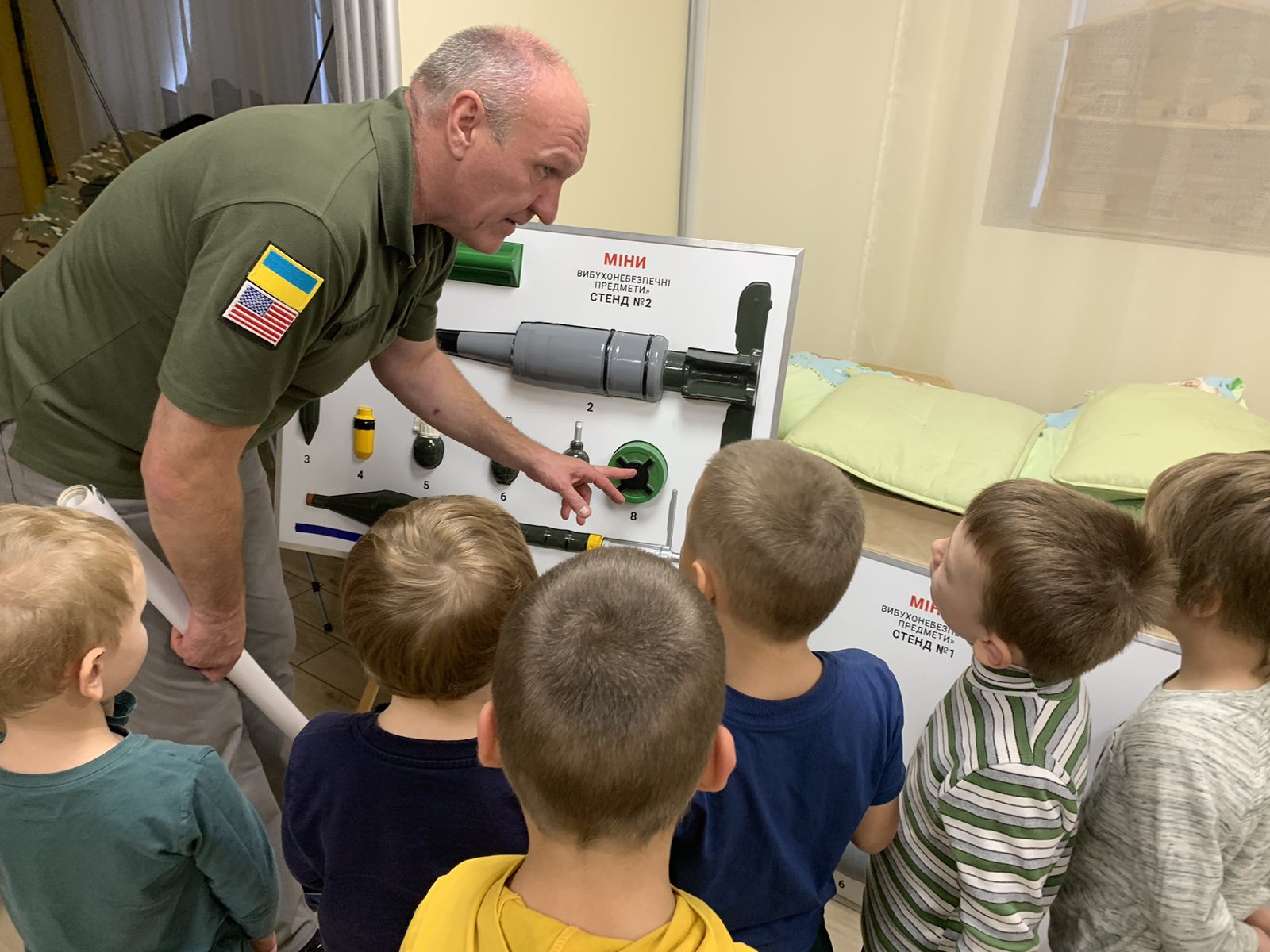 Foto, auf dem Kindergartenkinder Waffen erklärt bekommen